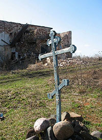 Крест у развалин Корнилиево-Комельского монастыря. На заднем плане – остатки трапезной палаты. Фото В. В. Шпака, 2007 г.