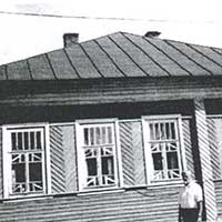 Улица Красная, 2 в Тотьме. Дом Коляды Александры Ивановны, бабушки Сергея Багрова, с которой Рубцов подружился и часто слушал, как она тихо мурлыкала, напевая старинные песни, склонившись над барабаном станка, выводя коклюшками кружевные узоры… На фото С. П. Багров у дома бабушки, в котором жил в 60-е гг.