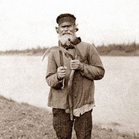 Старик-косарь правит косу-горбушу. Архангельская губерния, Онежский уезд, дер. Порог, 1910 г.

